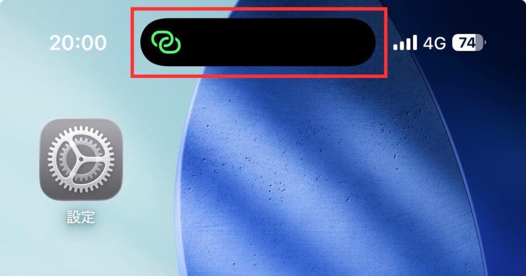 iPhoneのホーム画面上部（ダイナミックアイランド）に、インターネット共有中を示す緑色の鎖アイコンが表示されている状態のアップ。